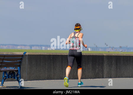 Southport, Merseyside. UK Weather. 25th July, 2017. Sun breaks through in the early afternoon, after a grey start to the day,  as tourists, cyclists, joggers and walkers enjoy light exercise along the seafront esplanade. On a clear day the views across the Ribble estuary to Blackpool and the Lake District are stunning.  Credit; MediaWorldimages/AlamyLiveNews Stock Photo