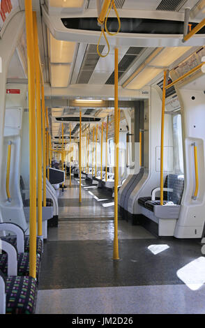 Interior of a new S7 carriage on London Underground's District Line - running above ground in East London, UK. Shows empty seats and passengers.