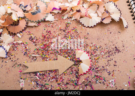 Arrow cut out of paper amid pencil shavings on canvas Stock Photo