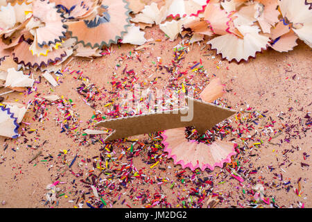 Arrow cut out of paper amid pencil shavings on canvas Stock Photo