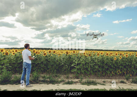 Young man watching and navigating a flying drone in blue clear sky Stock Photo