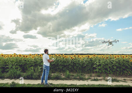 Young man watching and navigating a flying drone in blue clear sky Stock Photo