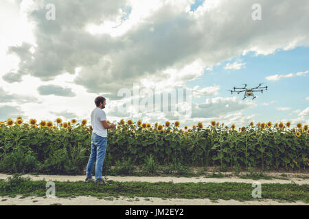 Young man watching and navigating a flying drone in blue clear sky Stock Photo