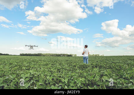 Technician farmer use wifi computer control agriculture drone on green field Stock Photo