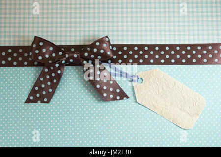 Brown and blue polka dots ribbon on light blue background with tag. Stock Photo