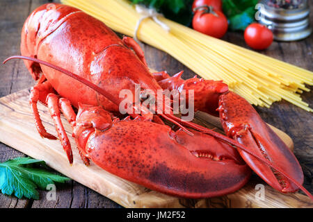 Delicious cooked lobster on wooden cutting board as a concept of Christmas cooking with a candle and fir or pine branches at the  background Stock Photo