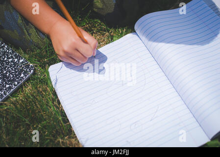A youth writes in a notebook for school education learning back to school. Stock Photo