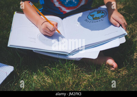 A youth writes in a notebook for school education learning back to school. Stock Photo