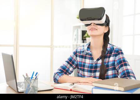 beautiful smiling girl working at home wearing virtual reality glasses enjoy 3d screen video imagine future life happily with computer and work note b Stock Photo