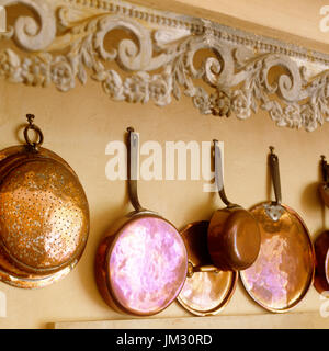 Pots and pans hanging on wall Stock Photo
