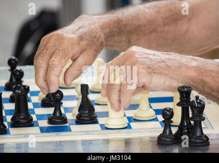 Elderly Spanish men playing chess outdoors in park Stock Photo