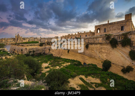 Manoel Island, Malta - Abandoned limestone fortress at the center of Manoel Island with Saint Paul's Cathedral and Valletta at the background Stock Photo