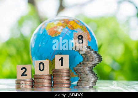 Globe behind a wooden numbers 2018 on growing stacks of coins using as growth business and achievement concept. Stock Photo