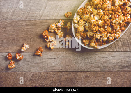 Caramel opcorn in bowl on the wooden table. Stock Photo