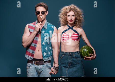 man with ice cream and woman with watermelon holding hands isolated on blue Stock Photo