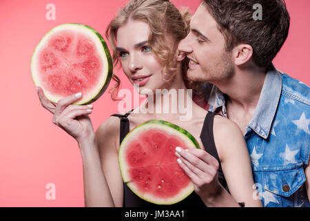 portrait of woman holding watermelon pieces with man near by isolated on pink Stock Photo