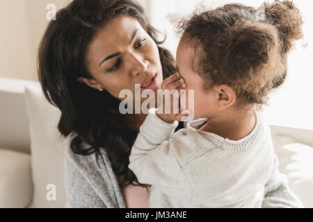 Mother looking at cute little crying daughter at home Stock Photo