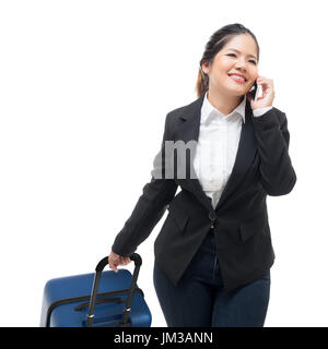 businesswoman talking on mobile phone while carrying luggage Stock Photo