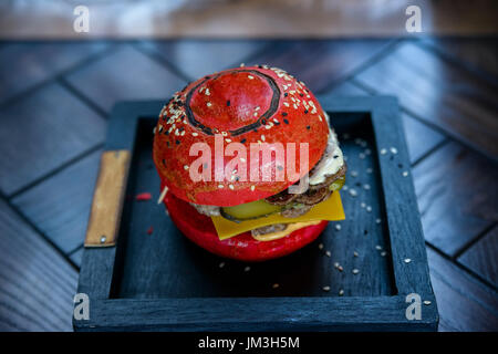 Close up delicious black burger with shrimps on wooden board in restaurant Stock Photo