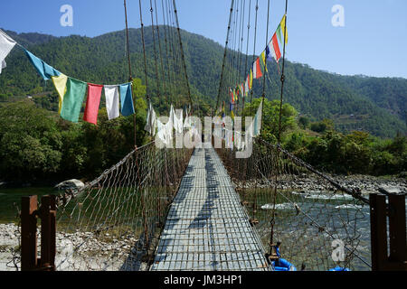 Suspension bridge across upper Punakha river with rafter getting ready to float, Bhutan Stock Photo