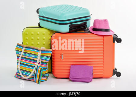Clutch bag, pink hat, suitcases. Woman summer pocketbook and beach accessories. Stock Photo