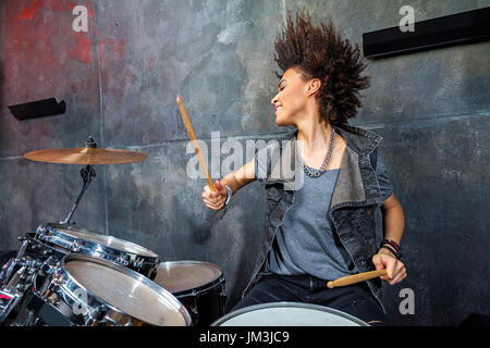 portrait of emotional woman playing drums in studio, drummer rock concept Stock Photo