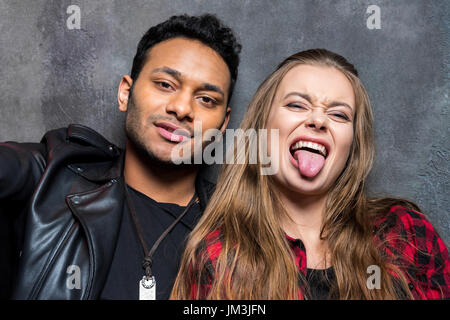 Portrait of young stylish man and woman sticking tongue out Stock Photo