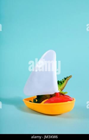 A dinosaur lost at sea on a toy boat like a noah's ark metaphor. Minimal Poetic still life photography Stock Photo