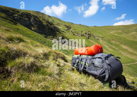 Mountain hiking backpack equipment on the grass with mountain landscape background Stock Photo