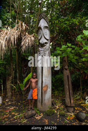 Ni-Vanuatu boy standing in front of slit gong drums in the jungle, Ambrym island, Olal, Vanuatu Stock Photo