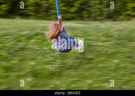 Girl on a zip line with green background. Entertainment. Recreational Stock Photo