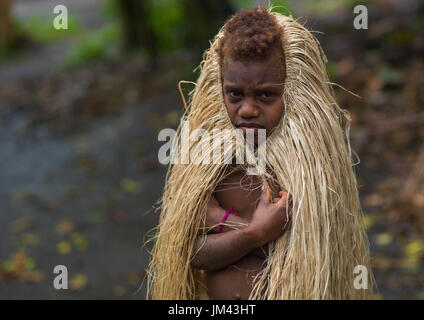 Young girl protecting herself from the rain with a traditional grass skirt, Tanna island, Yakel, Vanuatu Stock Photo
