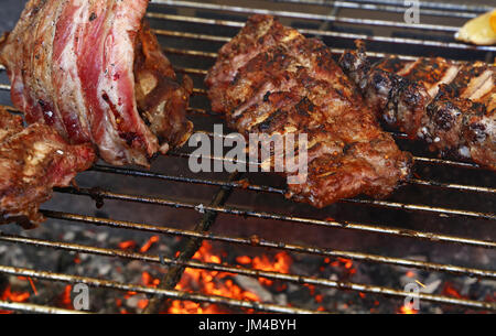 Several racks of pork spare ribs cooked on fire barbecue grill, close up, high angle view Stock Photo