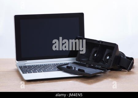 Laptop computer with open 3d VR headset resting on the keyboard in an entertainment and technology concept, close up low angle view Stock Photo