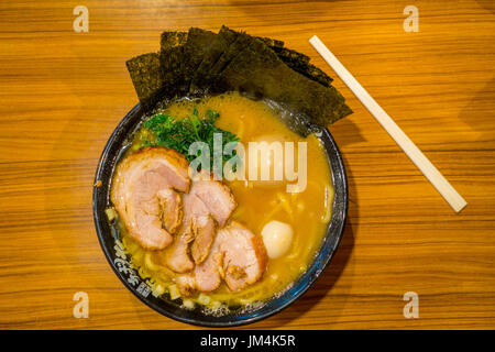 HAKONE, JAPAN - JULY 02, 2017: Delicious Japanese Ramen noodles with chopsticks over the soup in a wooden background, top view Stock Photo