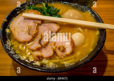 HAKONE, JAPAN - JULY 02, 2017: Delicious Japanese Ramen noodles with chopsticks over the soup in a wooden background Stock Photo