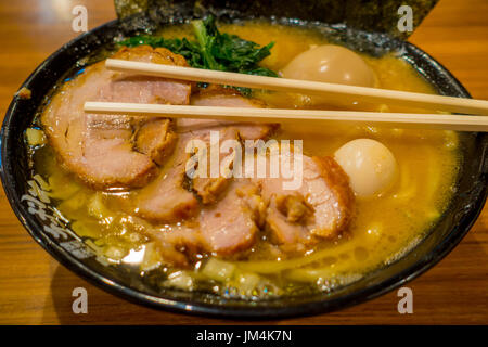 HAKONE, JAPAN - JULY 02, 2017: Delicious Japanese Ramen noodles with chopsticks over the soup in a wooden background Stock Photo