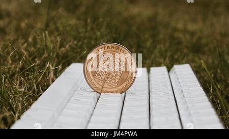 Cryptocurrency physical gold titan bitcoin with qr code on white keyboard in grass. Stock Photo