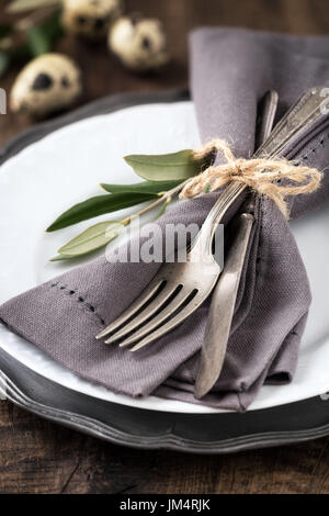 Easter table setting with vintage silverware with an olive branch on a white plate with quail eggs at the background Stock Photo