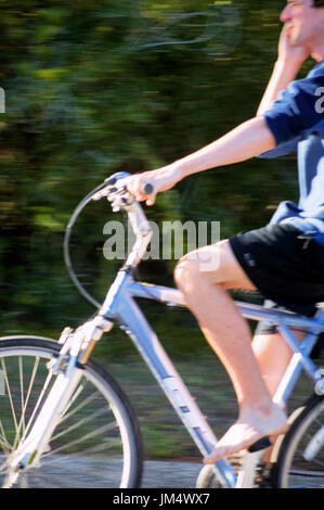 A blurred man talking on a phone on a bicycle. Stock Photo