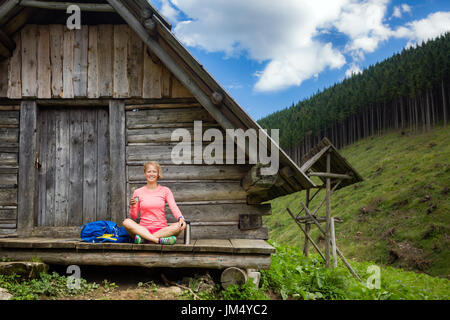 Young woman hiker camping, drink coffee or tea in beautiful Tatra mountains on hiking trip. Inspirational landscape in Poland. Active girl resting out Stock Photo