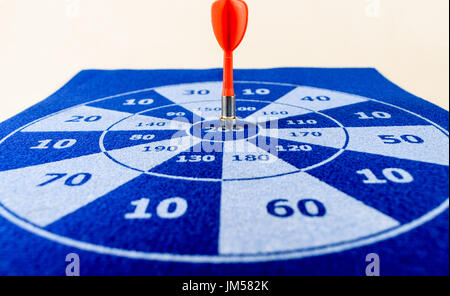 On target using a red dart and blue and white felt dart board Stock Photo