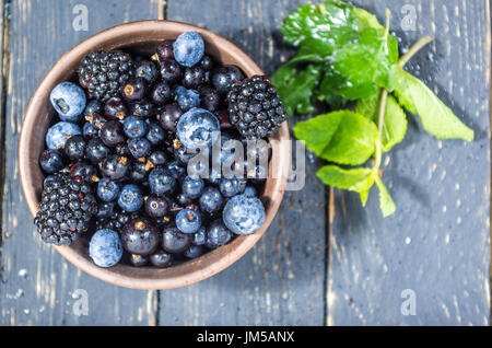 Forest berries in a clay plate. Berries with water drops. Low depth of field. Berry decoration. Stock Photo