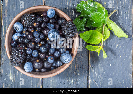 Forest berries in a clay plate. Berries with water drops. Deep depth of field. Berry decoration. Stock Photo