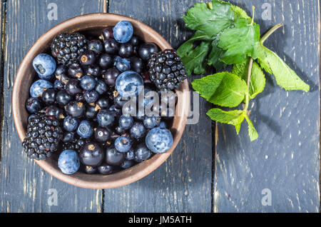 Forest berries in a clay plate. Deep depth of field. Flat lay. Berry decoration. Stock Photo
