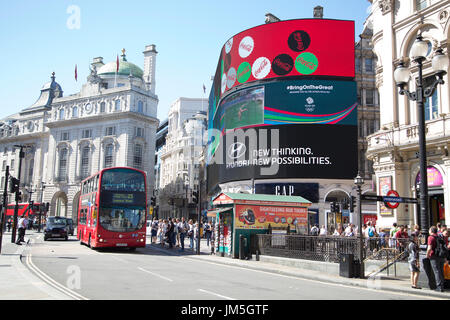 red bus passing busy street and large screen in piccadilly circus Stock Photo