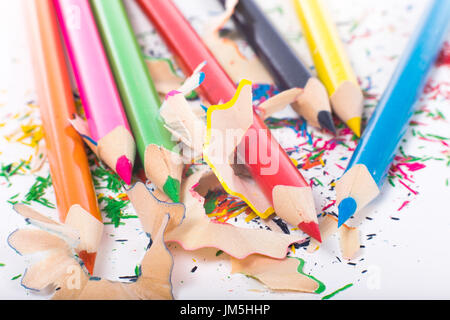 Bright color pencils over shavings after sharpening, close-up on white surface Stock Photo