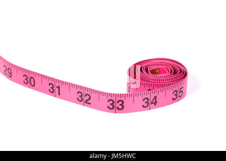 Pink measuring tape roll marked in inches with one end going outside the frame, close-up isolated on white background with copy space Stock Photo