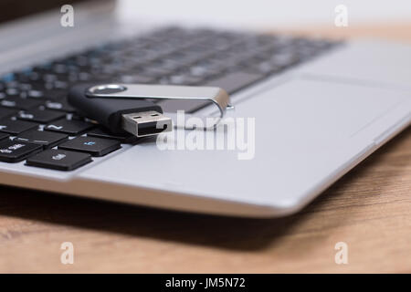 USB memory stick or flash drive on the keyboard of an open laptop viewed close up low angle with selective focus and copy space Stock Photo