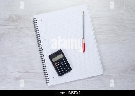 Overhead view of calculator and red pen on white spiral notepad Stock Photo